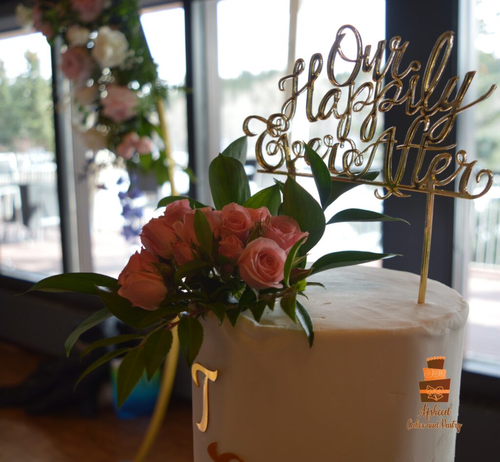 Custom cake topper and fresh pink roses on top of Tall two-tier buttercream wedding cake filled with chocolate ganache