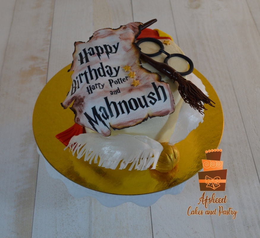 A small Harry Potter birthday cake decorated in Gryffindor colors with the Hogwarts crest, edible golden snitch, glasses, and a edible photo on the cake with the birthday girl name in harry potter fonts in a custom birthday decoration, created by Afsheed Cakes and Pastry in Calgary