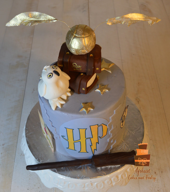 A Harry Potter birthday cake decorated with a hand made edible owl, spell books, edible golden snitch with edible gold HP logo , Wand, an edible image that shows a harry potter invitation letter and envelop 9 3/4 station platform created by Afsheed Cakes and Pastry in Calgary