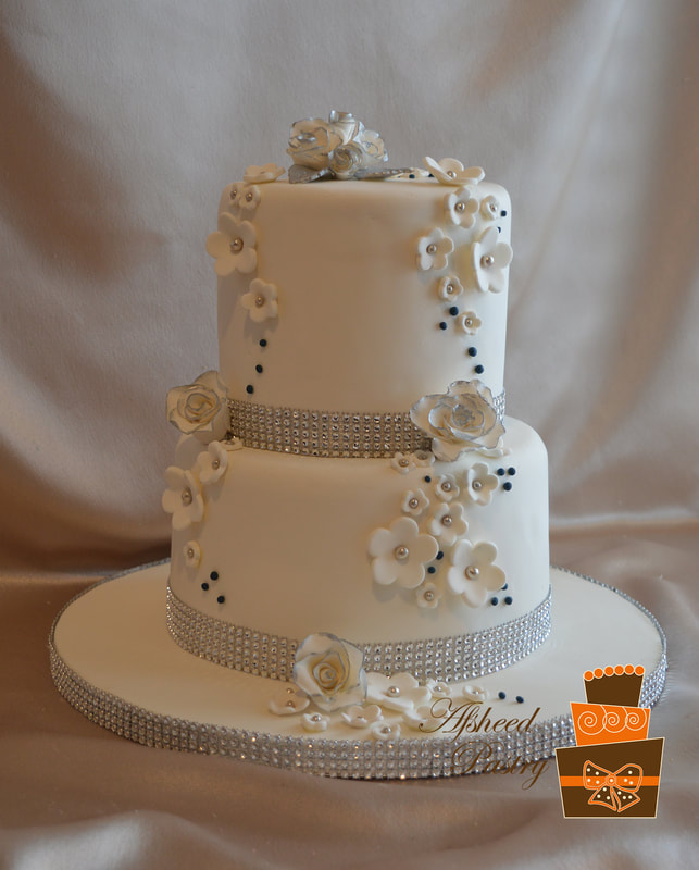 Wedding cake near me - Three-tier classic white fondant wedding cake featuring intricate edible lace patterns on each tier and delicate pearl piping borders by Afsheed cakes, in Calgary for local couples searching for the highest rated custom bakery to design an elegant and traditional center-piece.