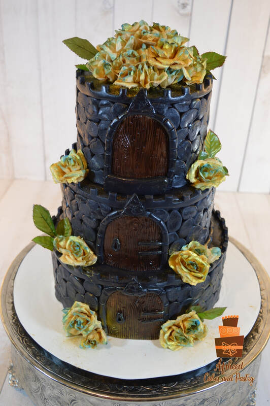 Medival Three tier wedding cake in shape of a black castle with gates and moat and hand made flowers. Made by Afsheed Cakes in Calgary